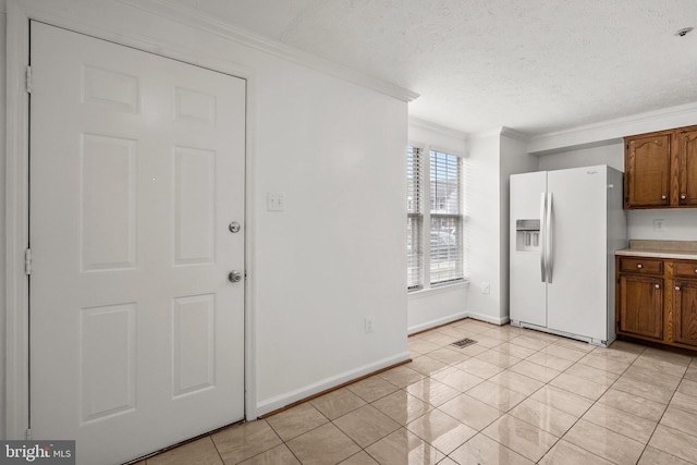 kitchen with a textured ceiling, crown molding, light tile patterned flooring, and white refrigerator with ice dispenser