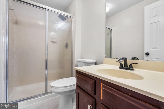 bathroom with tile patterned floors, vanity, an enclosed shower, and toilet