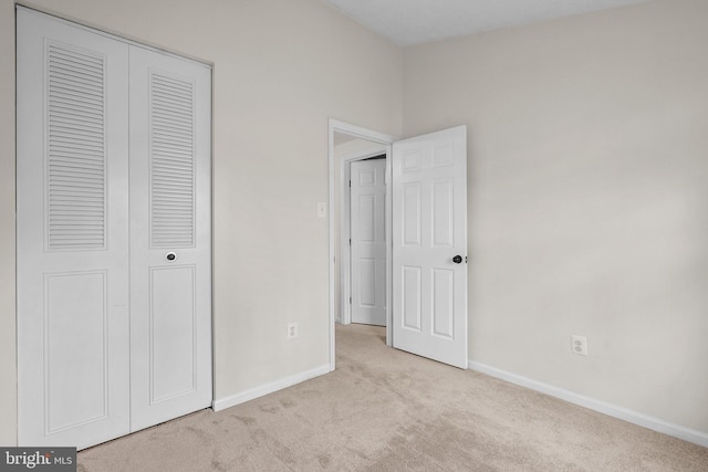 unfurnished bedroom with light carpet and a closet