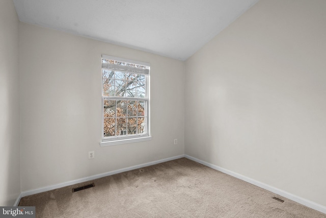 spare room with carpet flooring and lofted ceiling