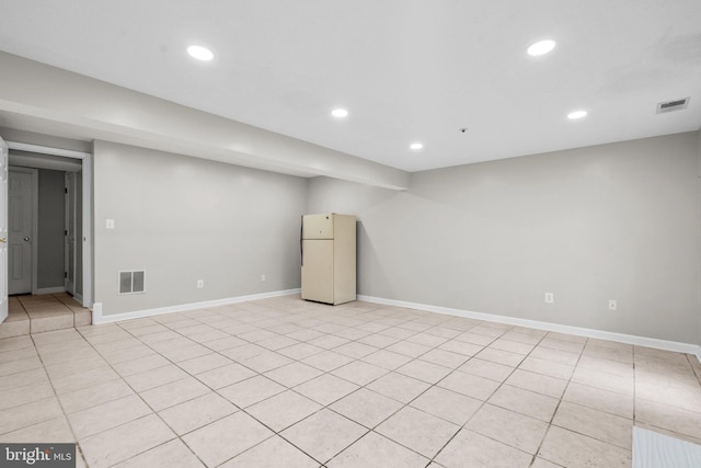 basement featuring white refrigerator and light tile patterned flooring