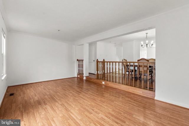 unfurnished room featuring hardwood / wood-style flooring, an inviting chandelier, and ornamental molding