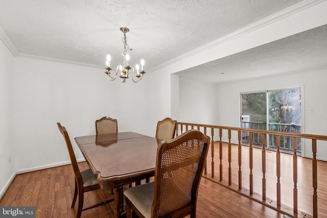 dining space featuring hardwood / wood-style floors, a textured ceiling, an inviting chandelier, and ornamental molding