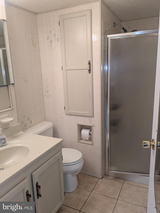 bathroom with an enclosed shower, tile patterned floors, vanity, tile walls, and toilet