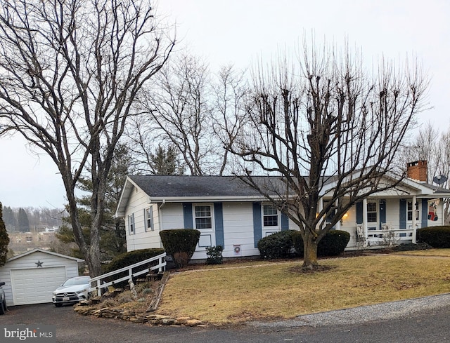 view of front of home with a garage, a front yard, an outbuilding, and covered porch