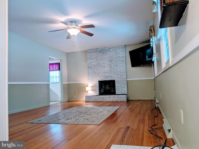 unfurnished living room with ceiling fan, a fireplace, and hardwood / wood-style flooring