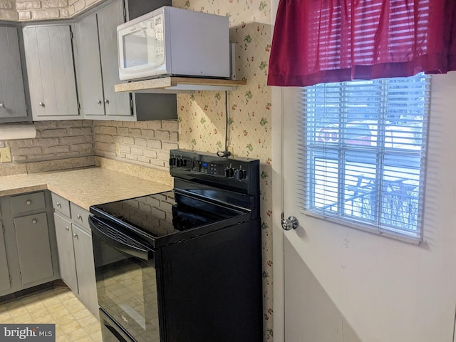 kitchen with gray cabinetry, exhaust hood, and black electric range oven