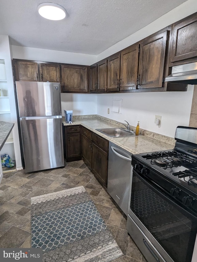 kitchen with appliances with stainless steel finishes, dark brown cabinetry, a textured ceiling, and sink