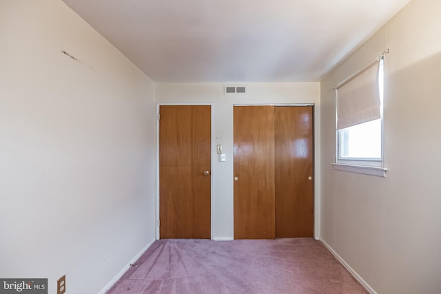 unfurnished bedroom featuring multiple closets and carpet floors