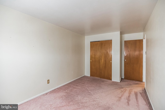 unfurnished bedroom featuring light colored carpet and a closet