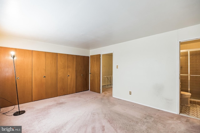 unfurnished bedroom featuring light colored carpet, ensuite bath, and a closet