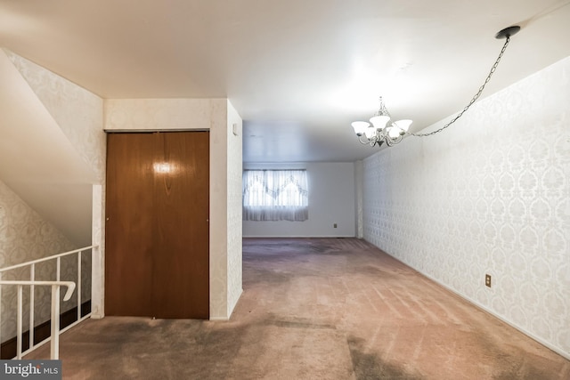 carpeted empty room with a notable chandelier