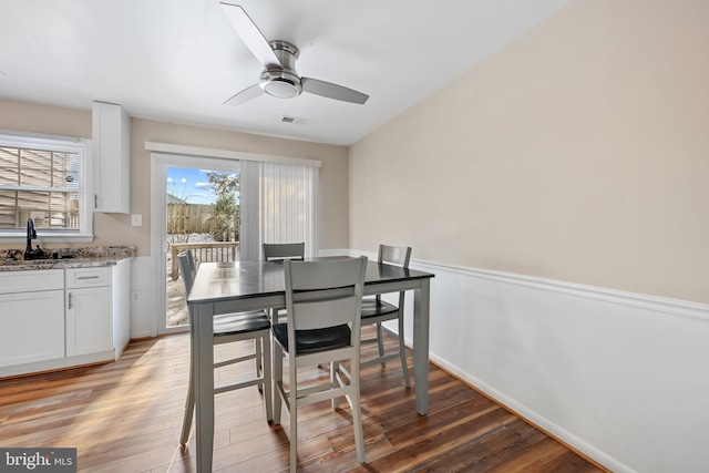 dining space featuring light hardwood / wood-style flooring, ceiling fan, and sink