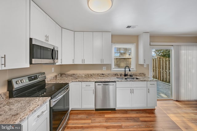 kitchen featuring stainless steel appliances, white cabinetry, light hardwood / wood-style floors, and sink