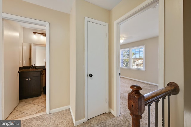 corridor featuring light colored carpet and sink