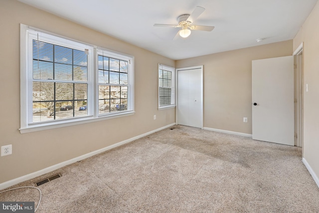 unfurnished bedroom with a closet, light colored carpet, and ceiling fan