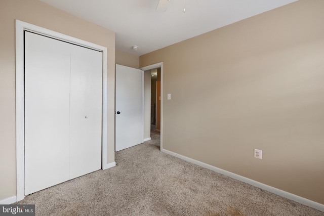 unfurnished bedroom featuring ceiling fan, a closet, and light carpet