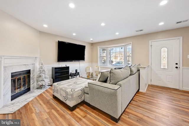 living room with a high end fireplace and light hardwood / wood-style floors