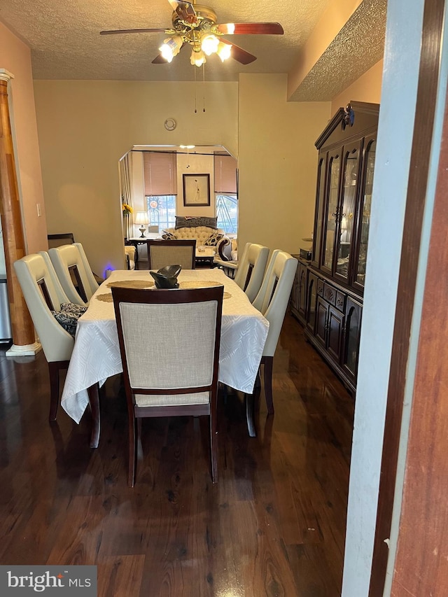 dining area featuring ceiling fan, dark wood-type flooring, and a textured ceiling