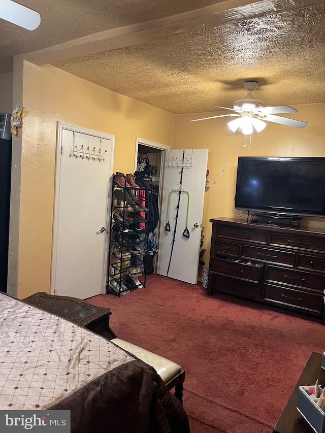 carpeted bedroom with ceiling fan and a textured ceiling