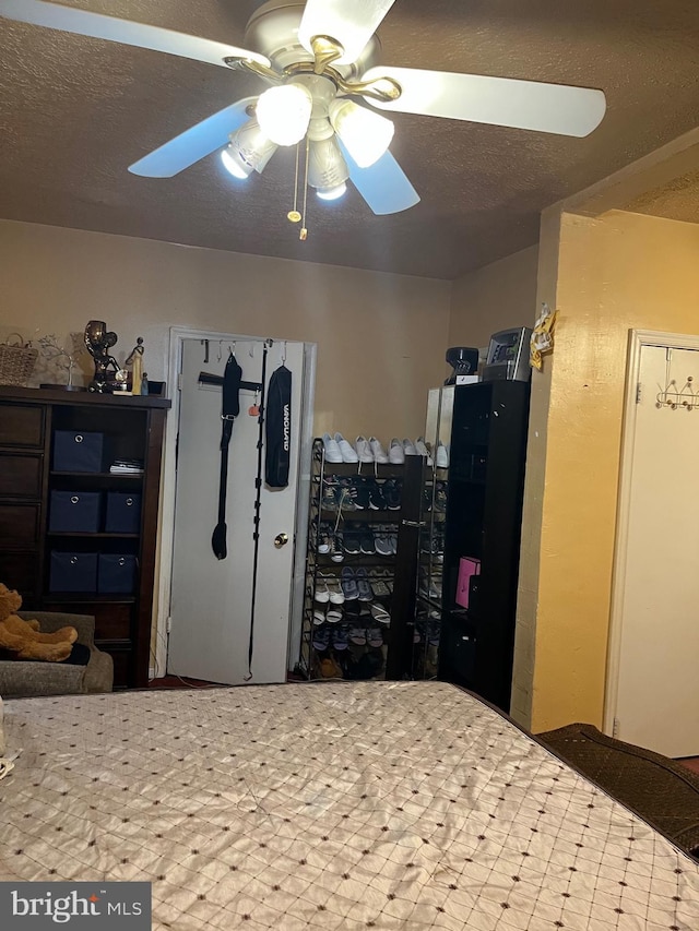 bedroom with ceiling fan and a textured ceiling