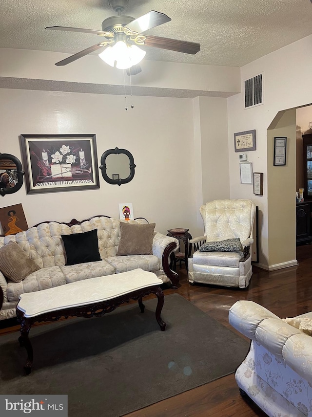 living room featuring a textured ceiling, ceiling fan, and dark hardwood / wood-style floors