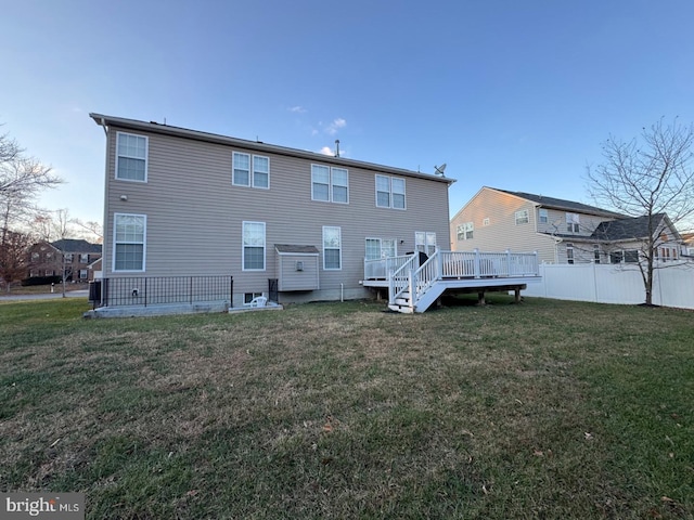 rear view of property featuring a lawn and a deck