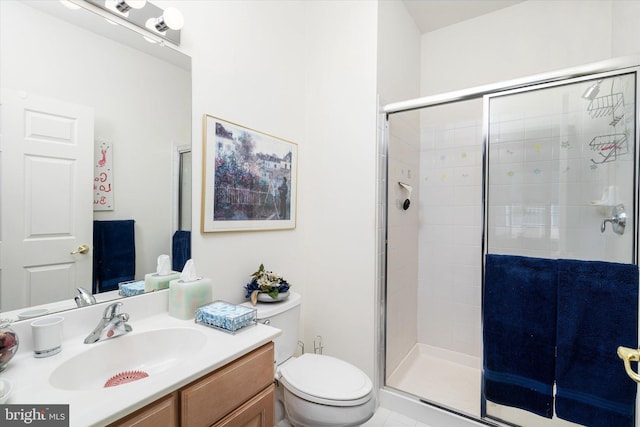 bathroom featuring toilet, vanity, and a shower with shower door