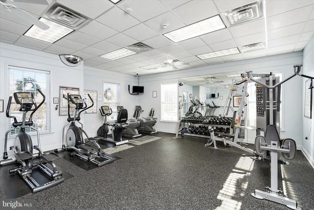 exercise room with ceiling fan and a drop ceiling