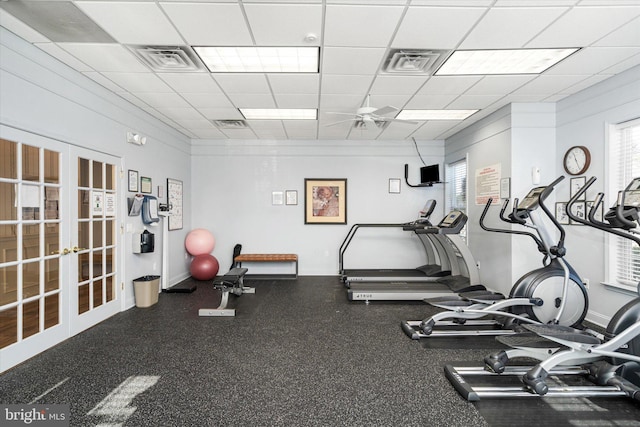 exercise room with ceiling fan, a drop ceiling, and french doors