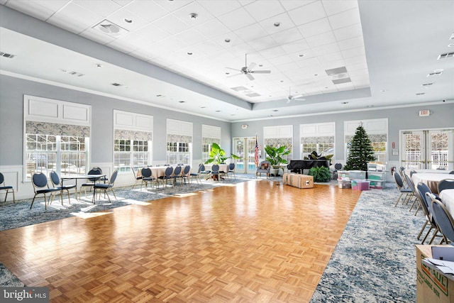 living room with ceiling fan, crown molding, a raised ceiling, and light parquet floors