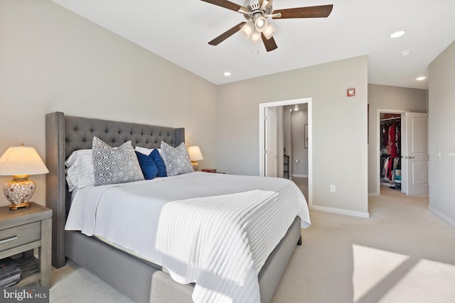 bedroom featuring ceiling fan, ensuite bathroom, light carpet, a walk in closet, and a closet