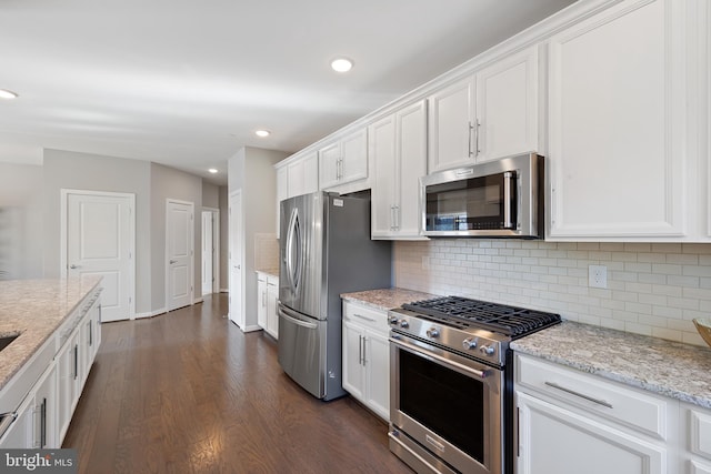 kitchen with light stone counters, tasteful backsplash, dark hardwood / wood-style floors, stainless steel appliances, and white cabinets