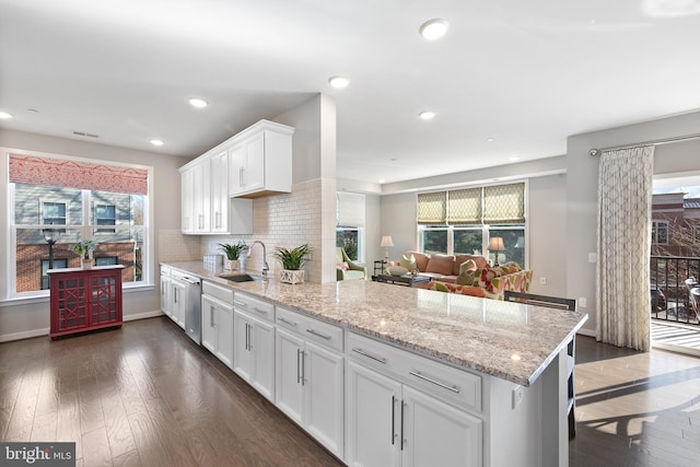 kitchen with dark wood-type flooring, a breakfast bar, sink, dishwasher, and white cabinets