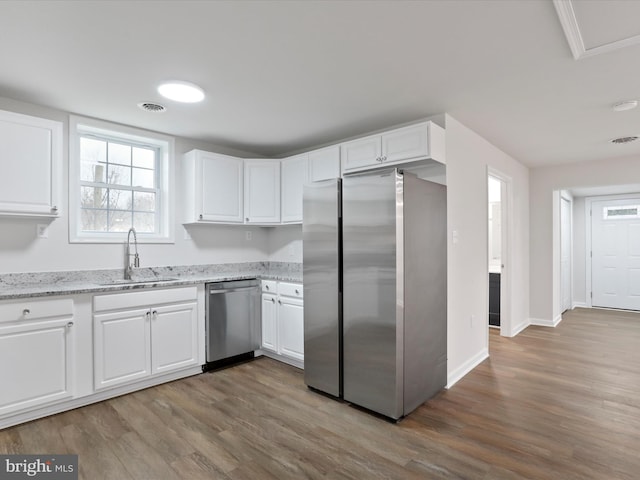 kitchen with appliances with stainless steel finishes, light stone counters, white cabinetry, and sink