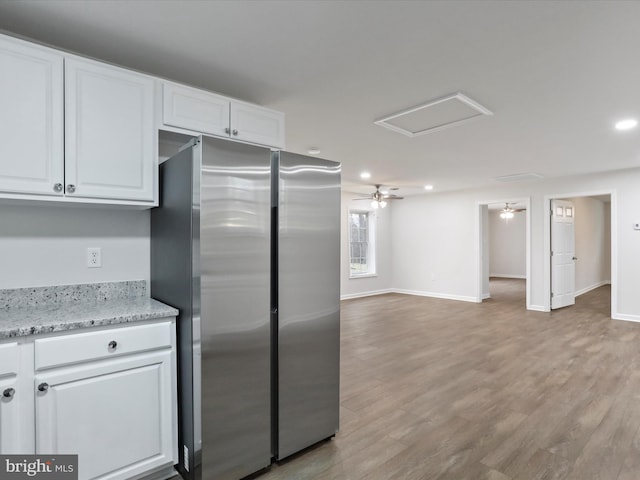 kitchen featuring white cabinets, ceiling fan, light wood-type flooring, light stone counters, and stainless steel refrigerator