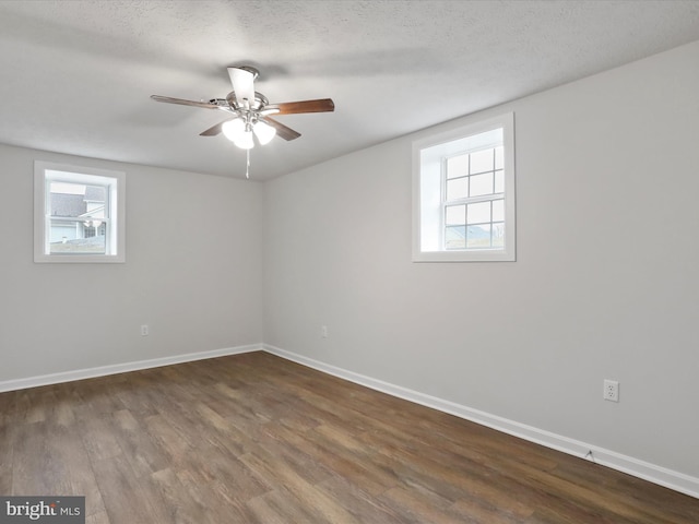 empty room featuring a wealth of natural light, dark hardwood / wood-style floors, and a textured ceiling