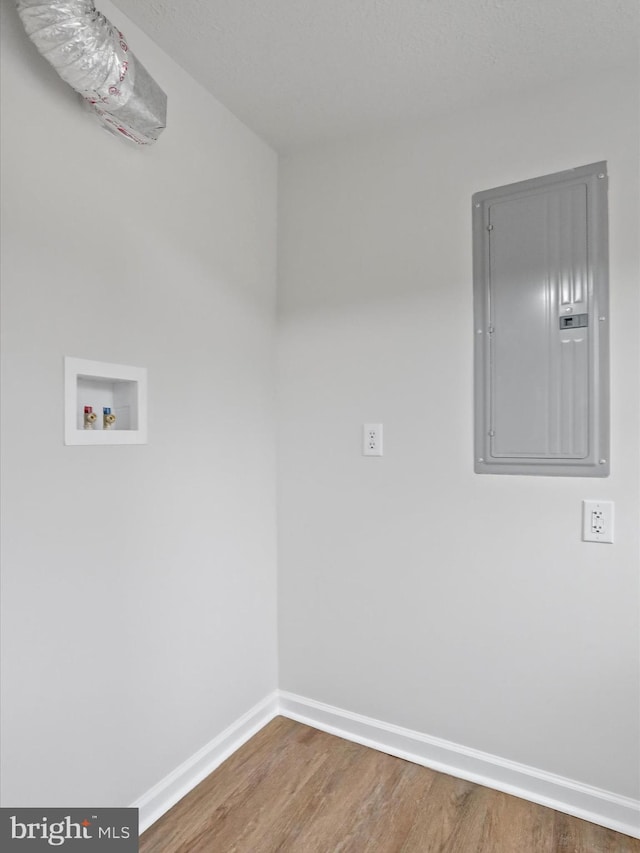 washroom with hookup for a washing machine, electric panel, and wood-type flooring