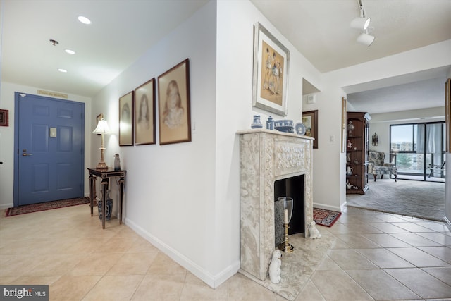 carpeted foyer entrance featuring a fireplace and rail lighting