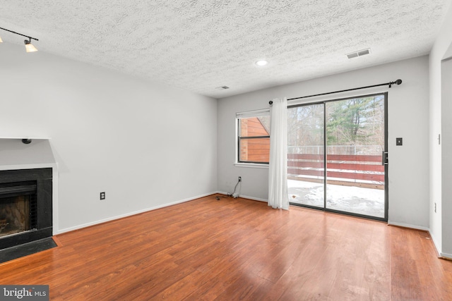 unfurnished living room with a textured ceiling and light hardwood / wood-style flooring