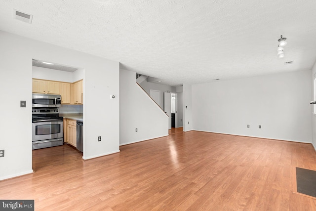 unfurnished living room with light hardwood / wood-style floors and a textured ceiling