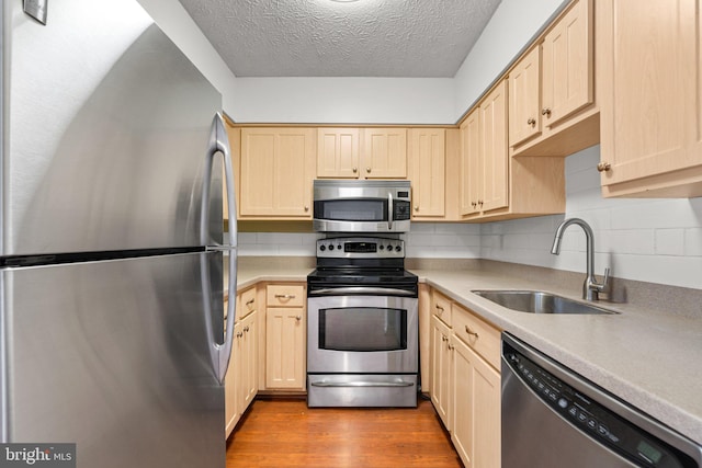 kitchen with tasteful backsplash, sink, light brown cabinets, and stainless steel appliances