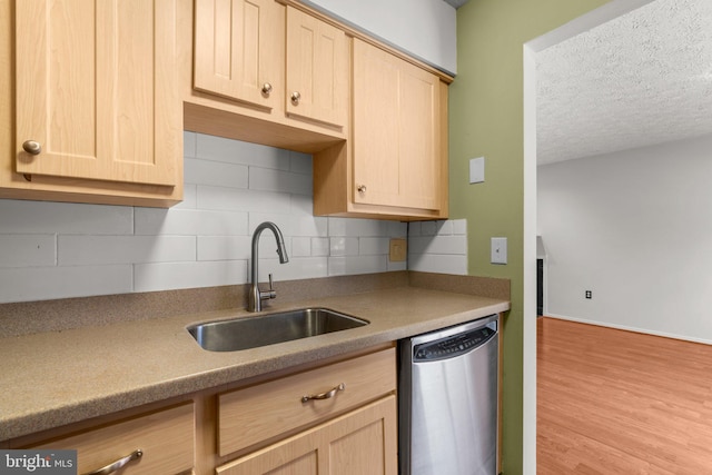 kitchen featuring stainless steel dishwasher, backsplash, sink, and light brown cabinetry