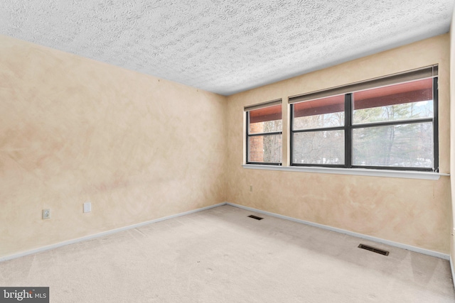 carpeted empty room featuring a textured ceiling