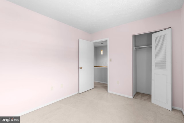 unfurnished bedroom featuring light colored carpet, a textured ceiling, and a closet