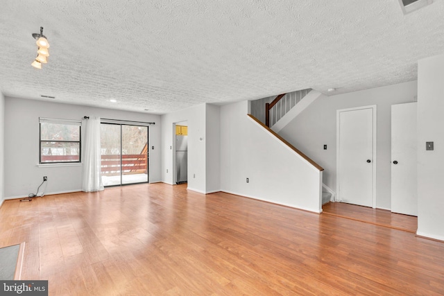 unfurnished living room with a textured ceiling and light hardwood / wood-style floors