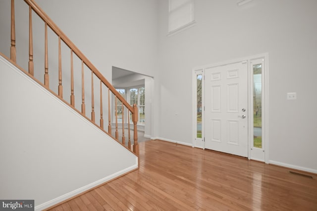 foyer featuring wood-type flooring and a high ceiling