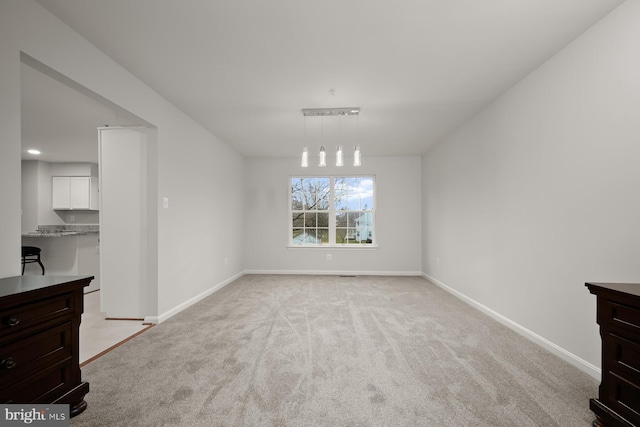 unfurnished dining area with light colored carpet