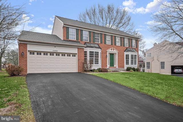 colonial house featuring a front yard and a garage