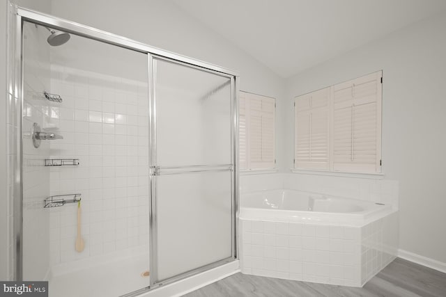 bathroom featuring separate shower and tub, hardwood / wood-style floors, and vaulted ceiling